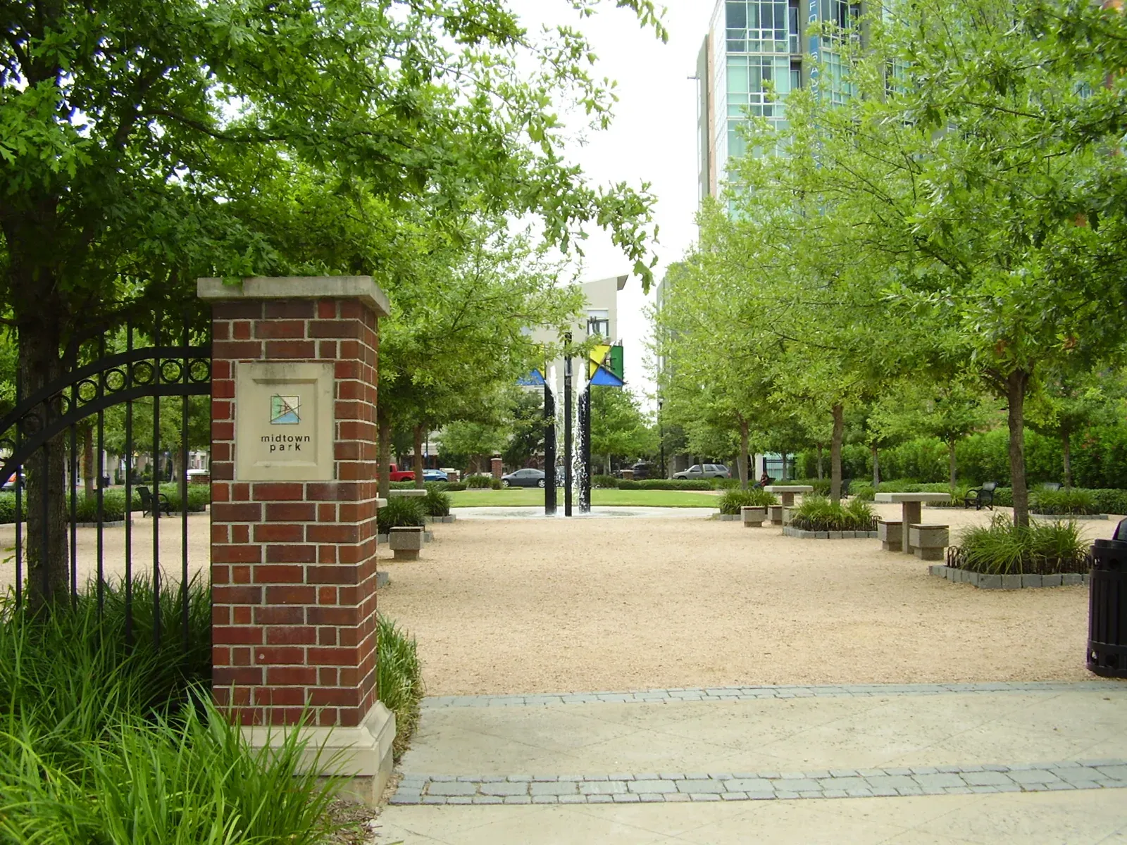 Entrance to Midtown Park in Houston, with trees and a gravel path